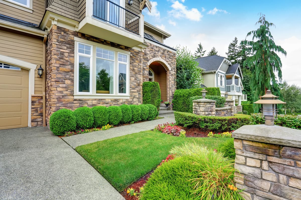 Beautiful curb appeal of a house with stone trim and perfectly trimmed shrubs
